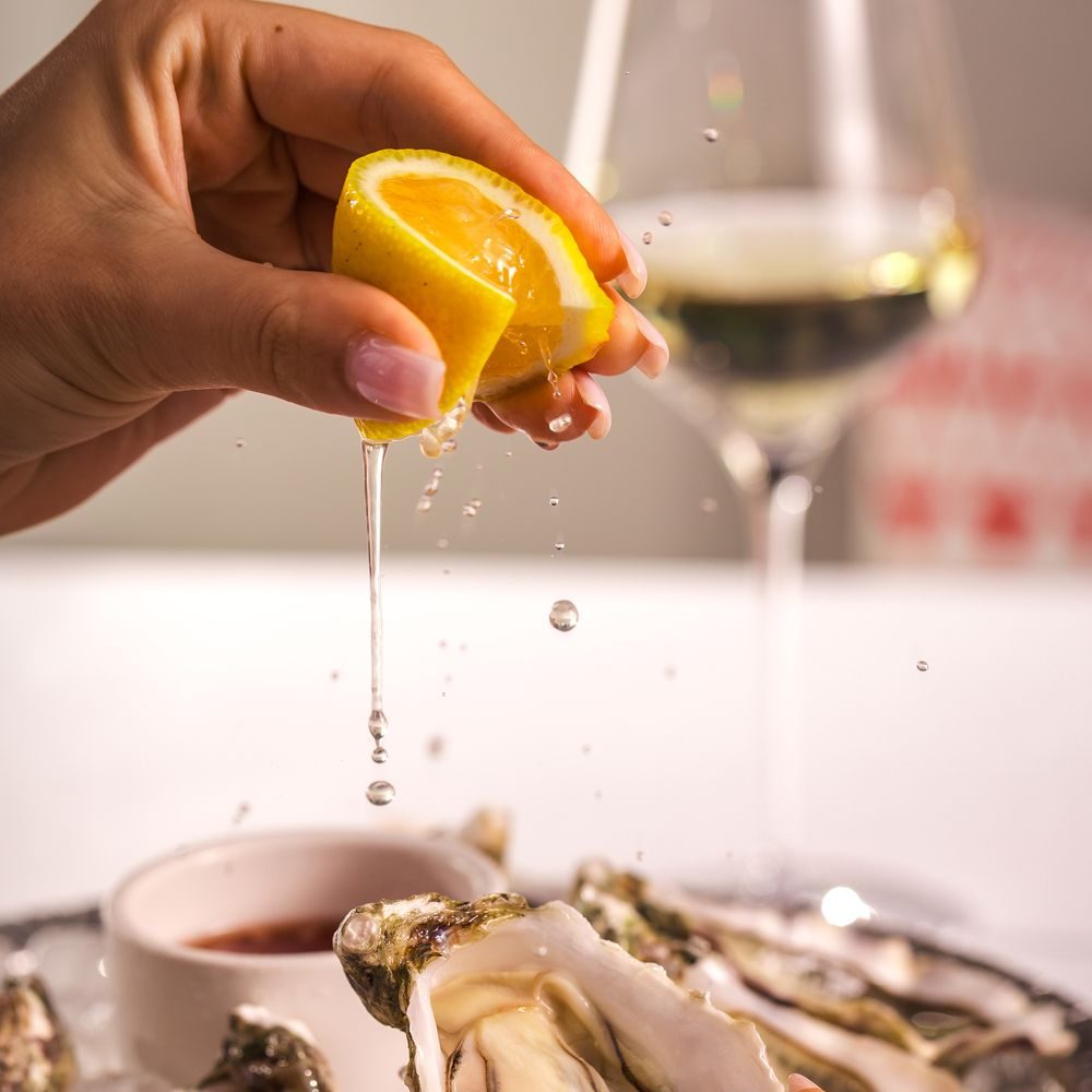 Lemon over an oyster and a glass of white
