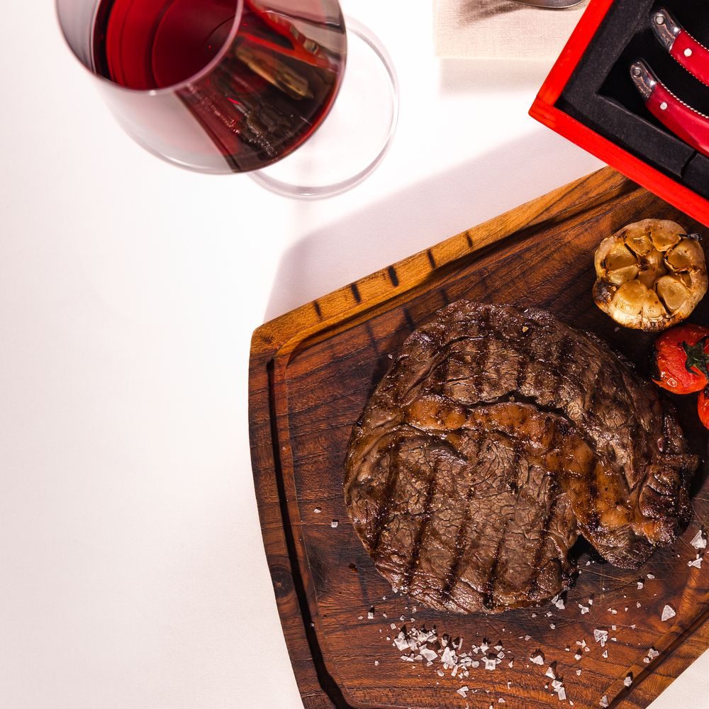 Ribeye on the board with a glass of red, top view