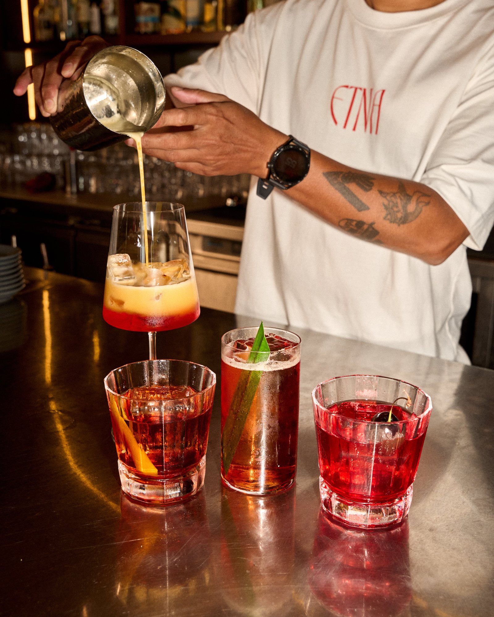 Pouring a Negroni at the ETNA bar, four cocktails on the counter